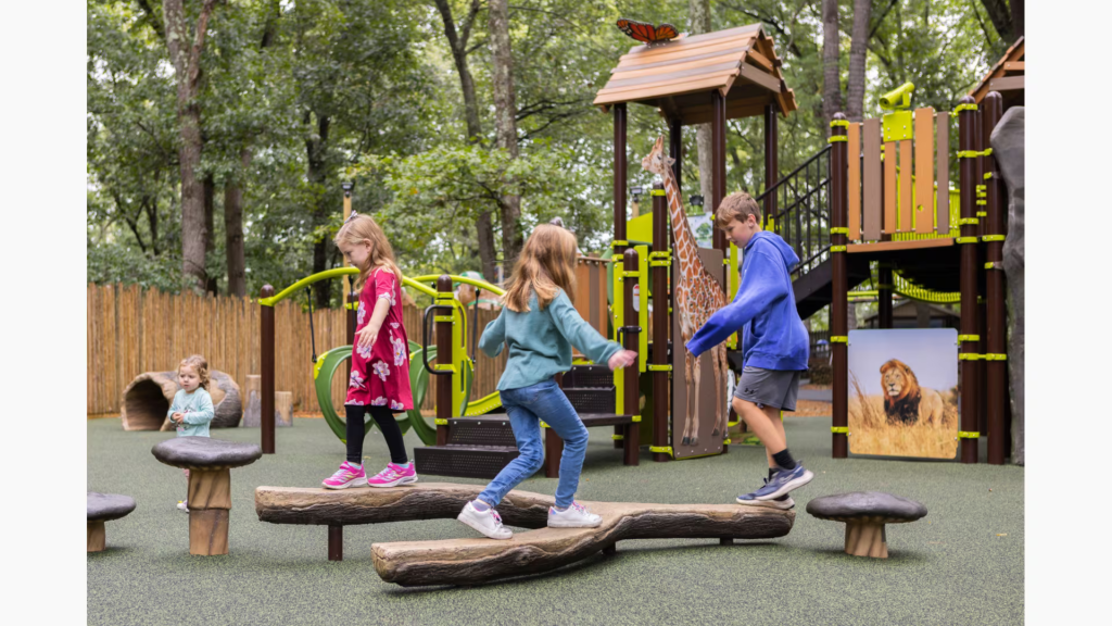 Children running across imitation logs on a playground.