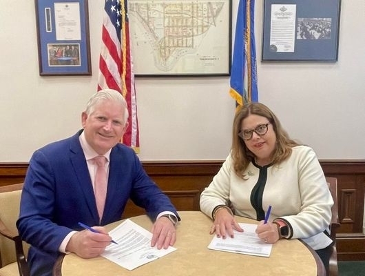 Clerk Mickey Kearns and Judge Amy C. Martoche seated at a table signing a letter to request expanded mandatory e-filing for Erie County cases.
